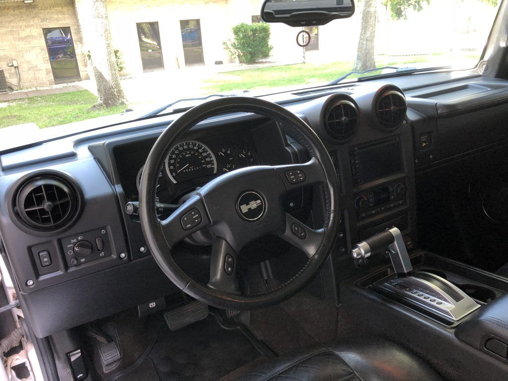The interior of a hummer h2 with a steering wheel and dashboard.