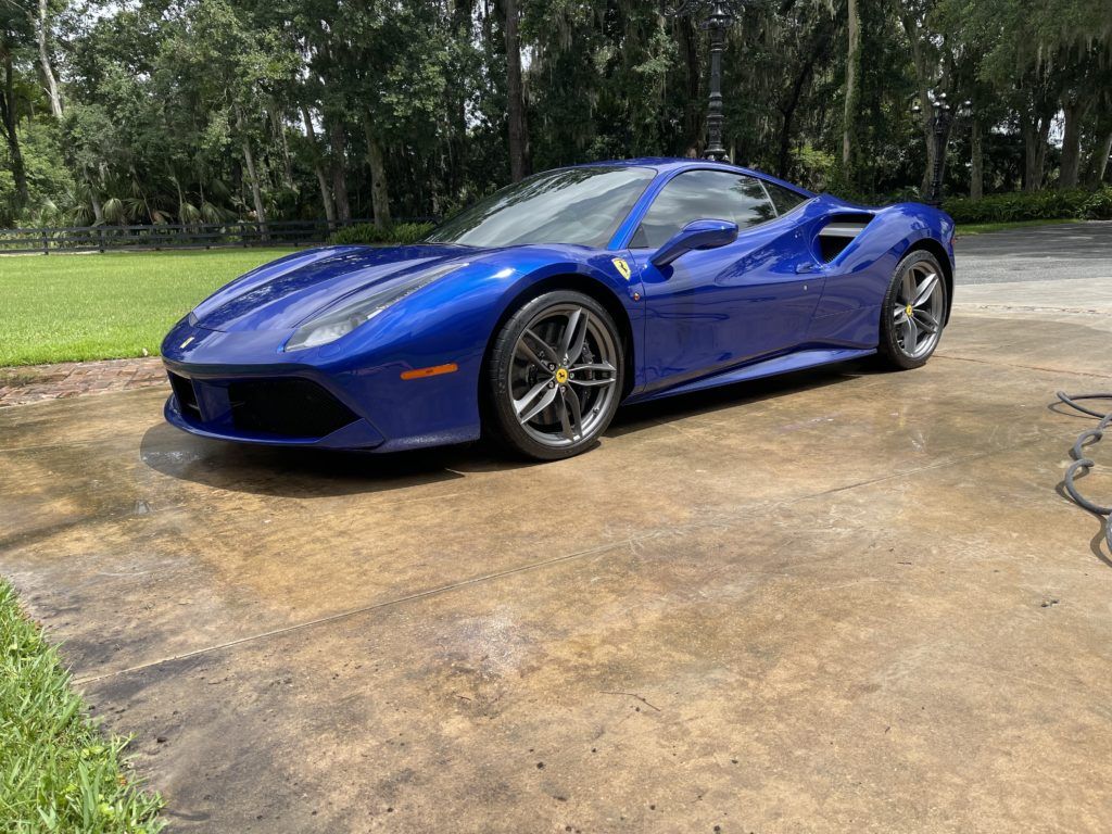 A blue ferrari 488 gtb is parked in a driveway.