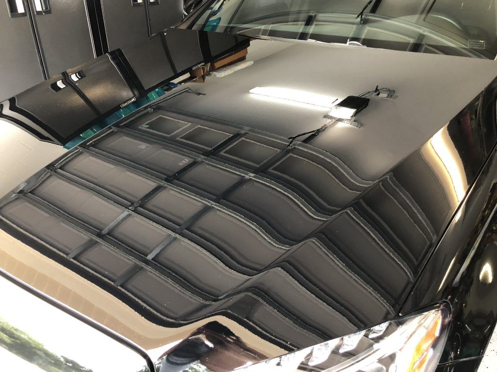 The hood of a black car is reflected in the windshield.