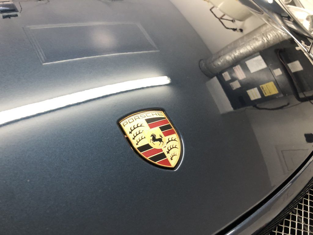 A close up of a porsche emblem on the hood of a car.