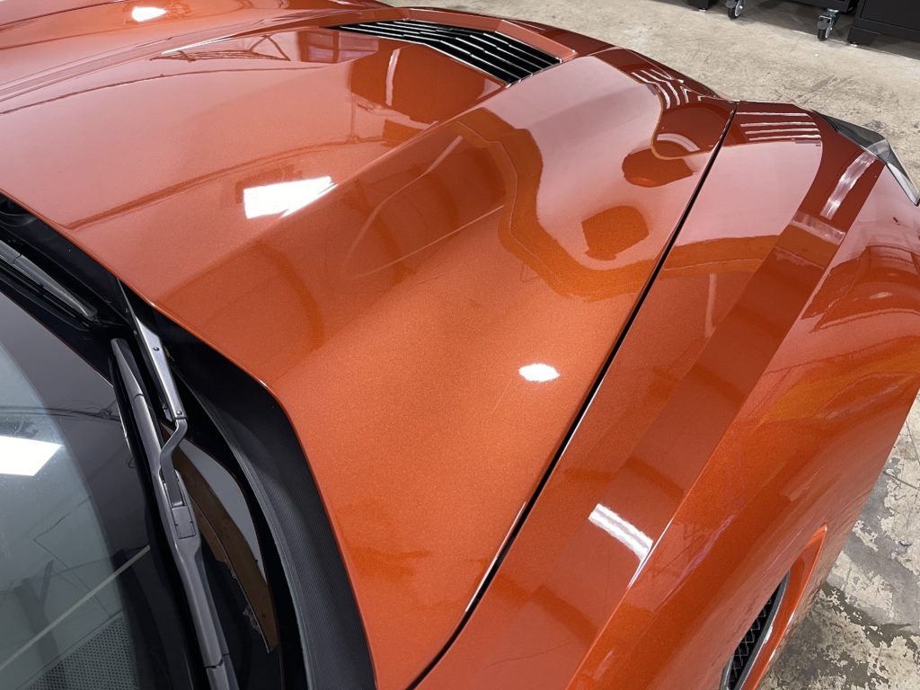 A close up of the hood of an orange sports car