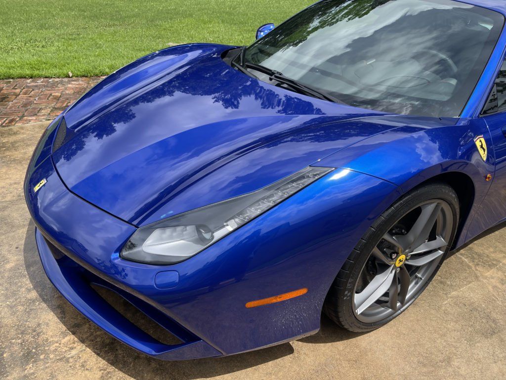 A blue ferrari 488 gtb is parked in a driveway.