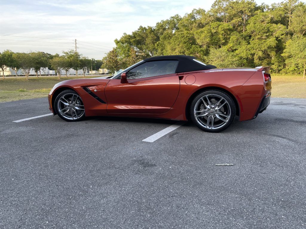 A red corvette convertible is parked in a parking lot.