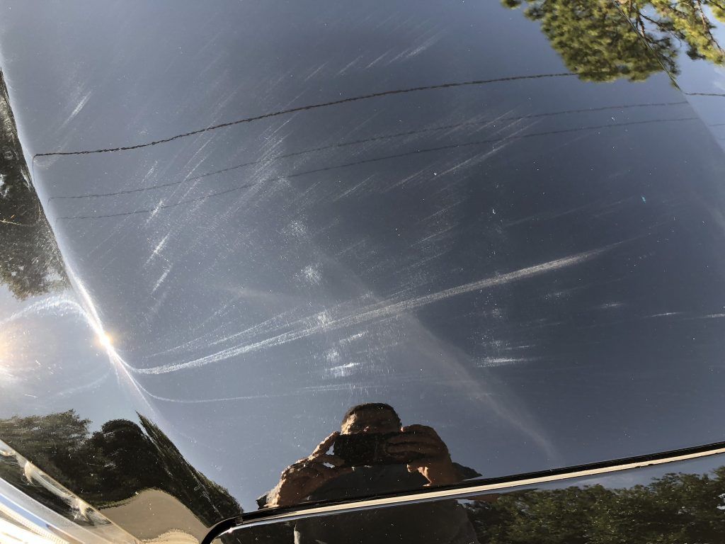 A person is taking a picture of the hood of a car.