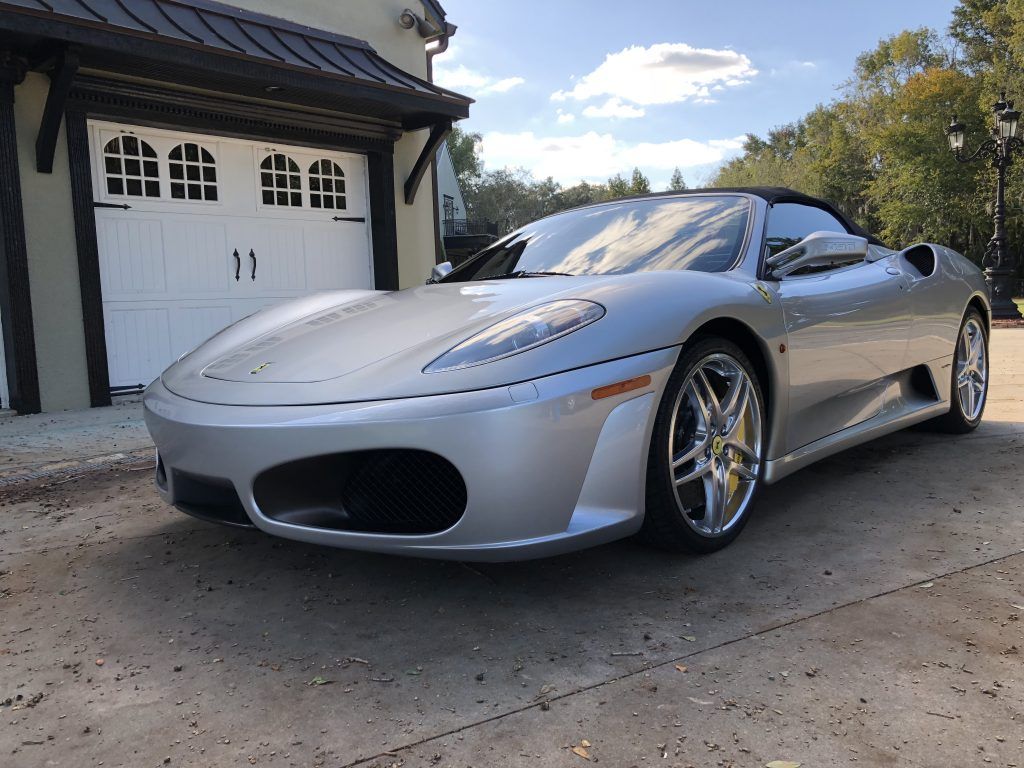 A silver sports car is parked in front of a garage door.
