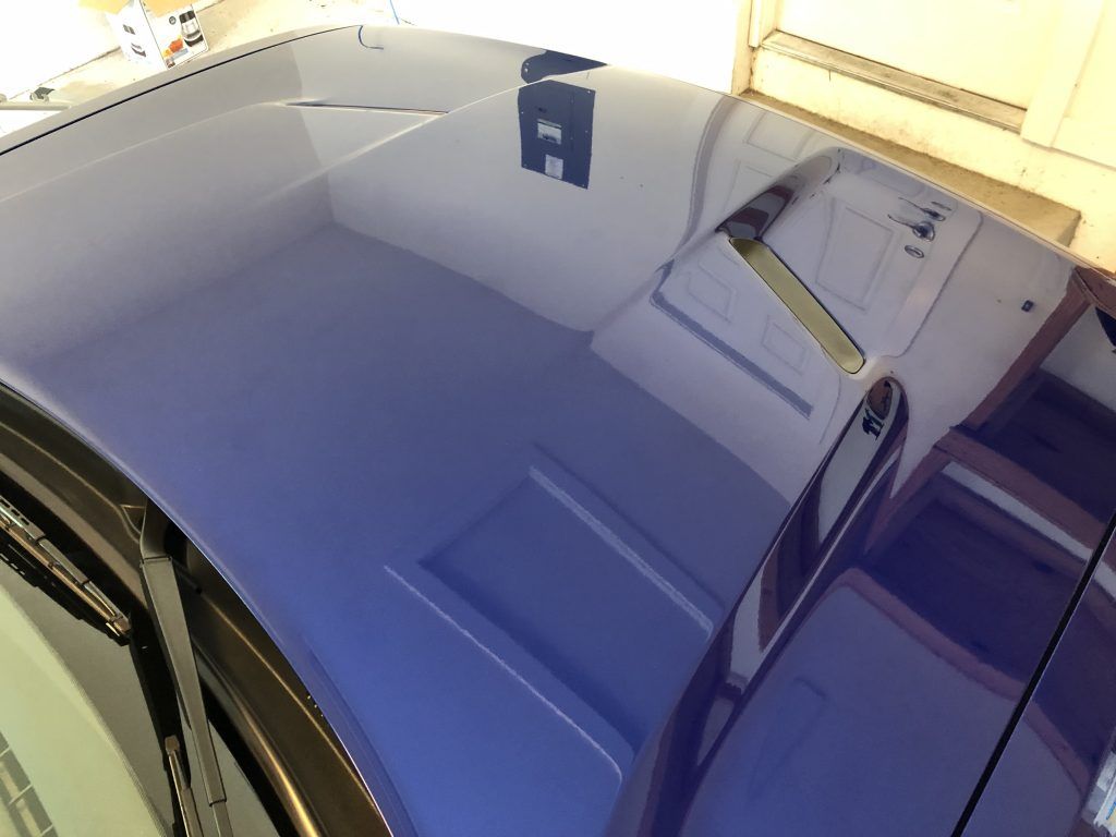 The roof of a blue car is reflected in the window