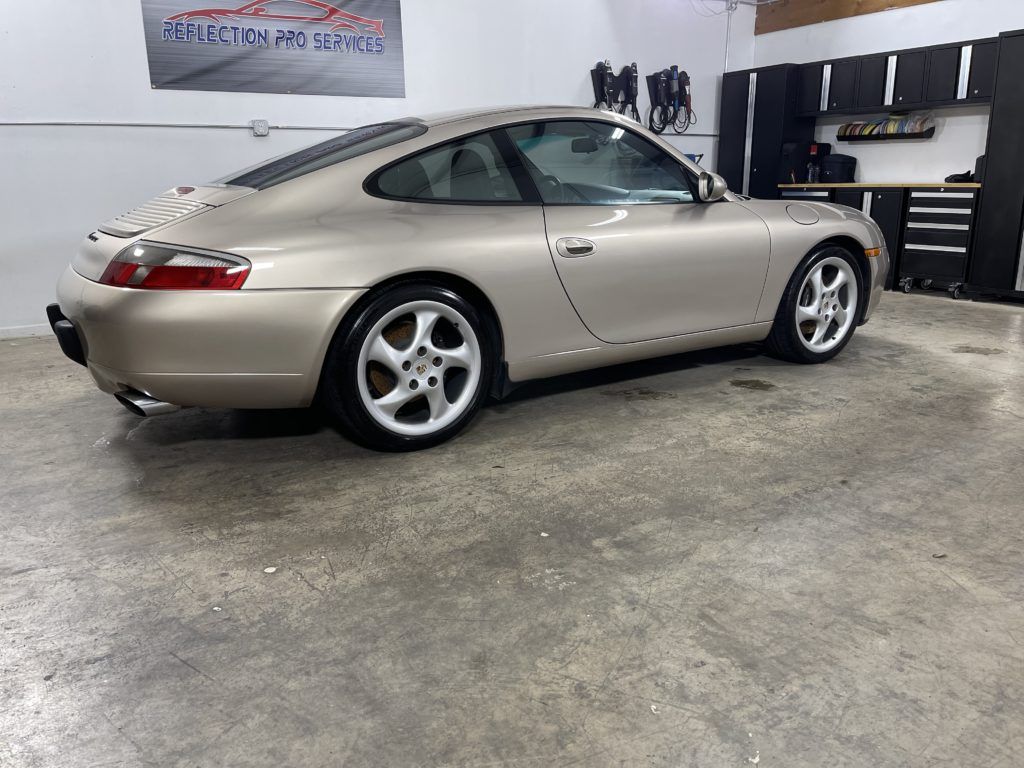 A gold porsche 911 is parked in a garage.