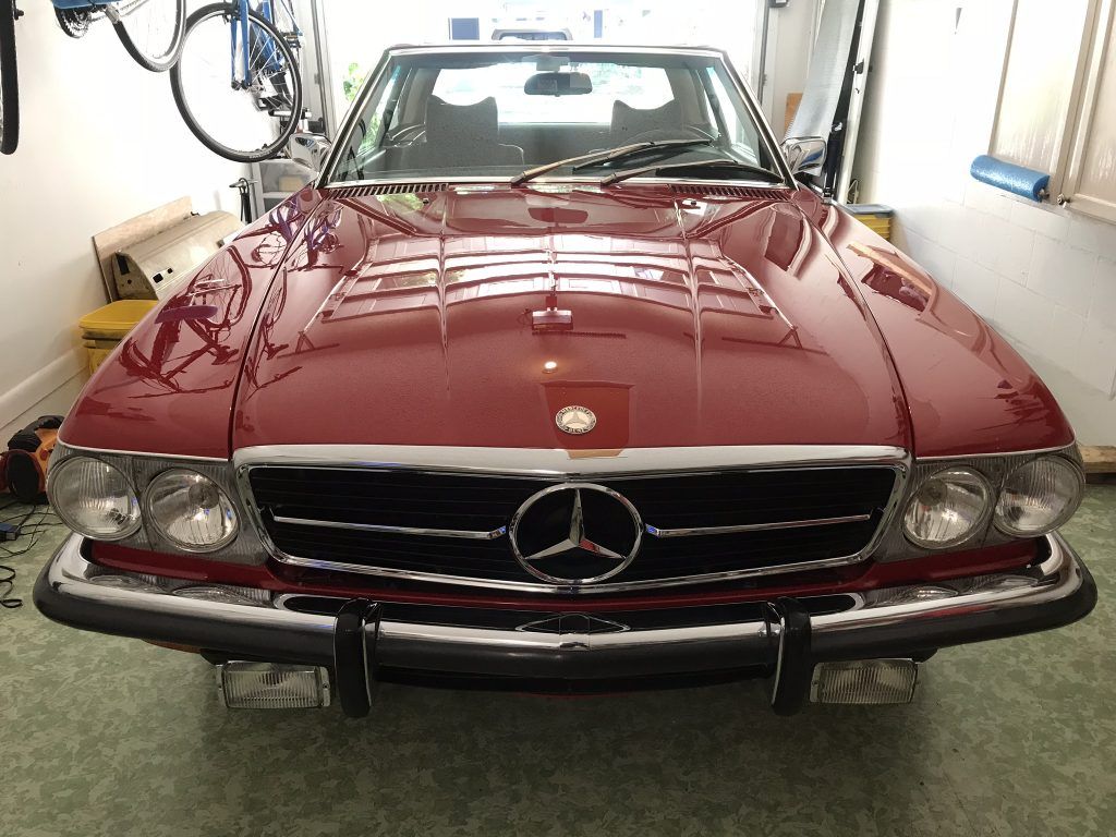 A red mercedes benz is parked in a garage.