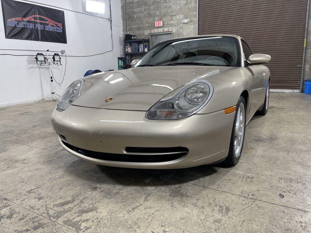 A gold porsche 911 is parked in a garage.
