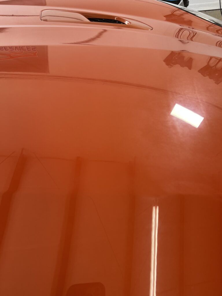 A close up of a red car hood in a garage.