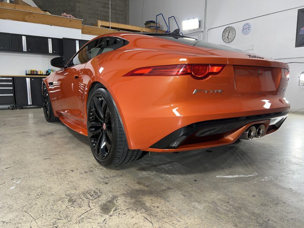 An orange sports car is parked in a garage.