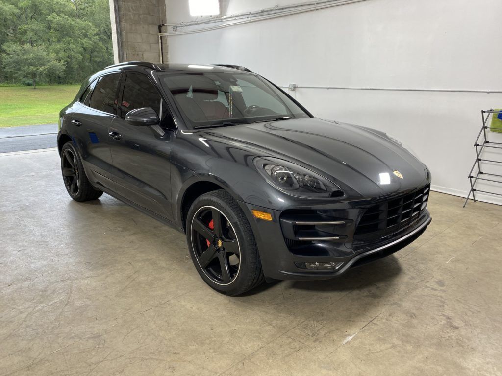 A black porsche macan gts is parked in a garage.