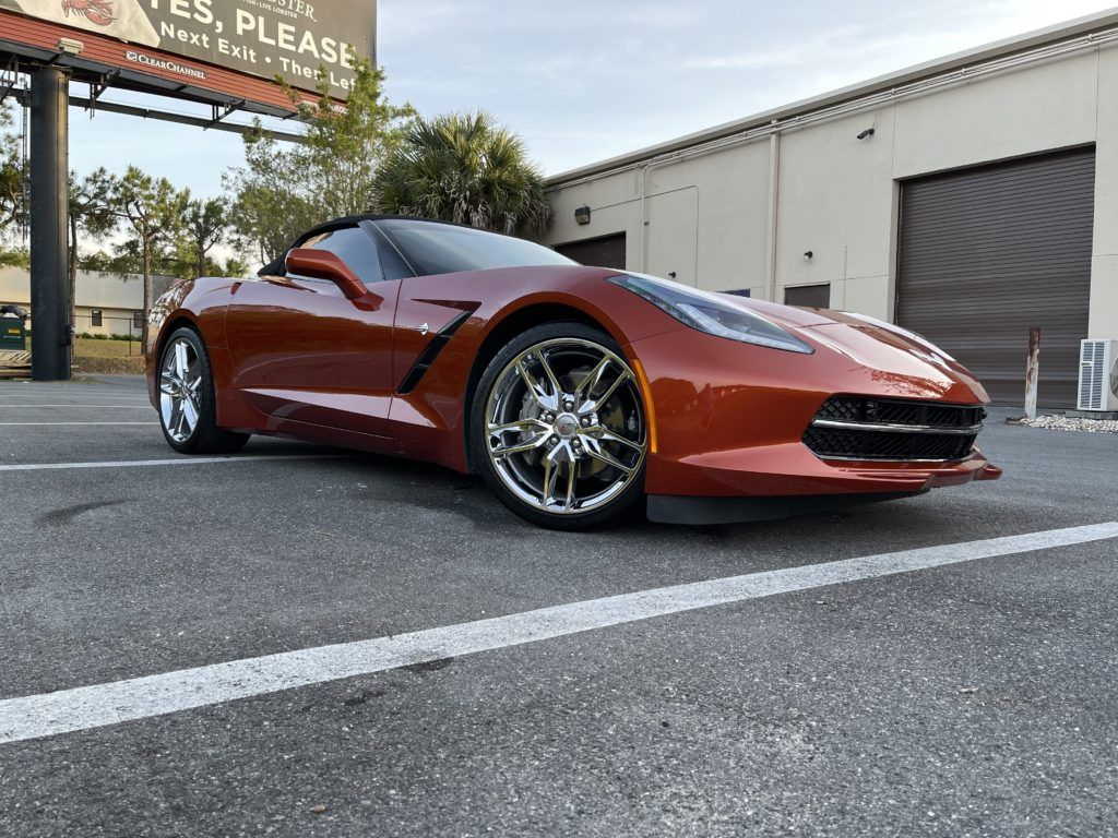 A red sports car is parked in a parking lot in front of a building.