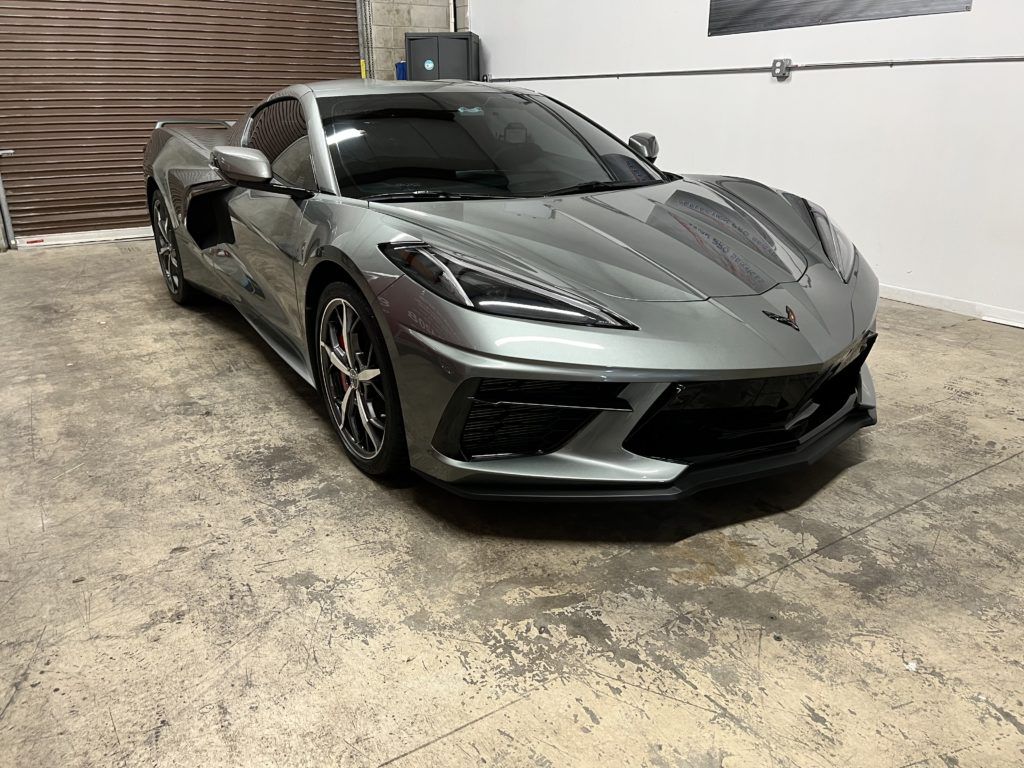 A gray corvette is parked in a garage.