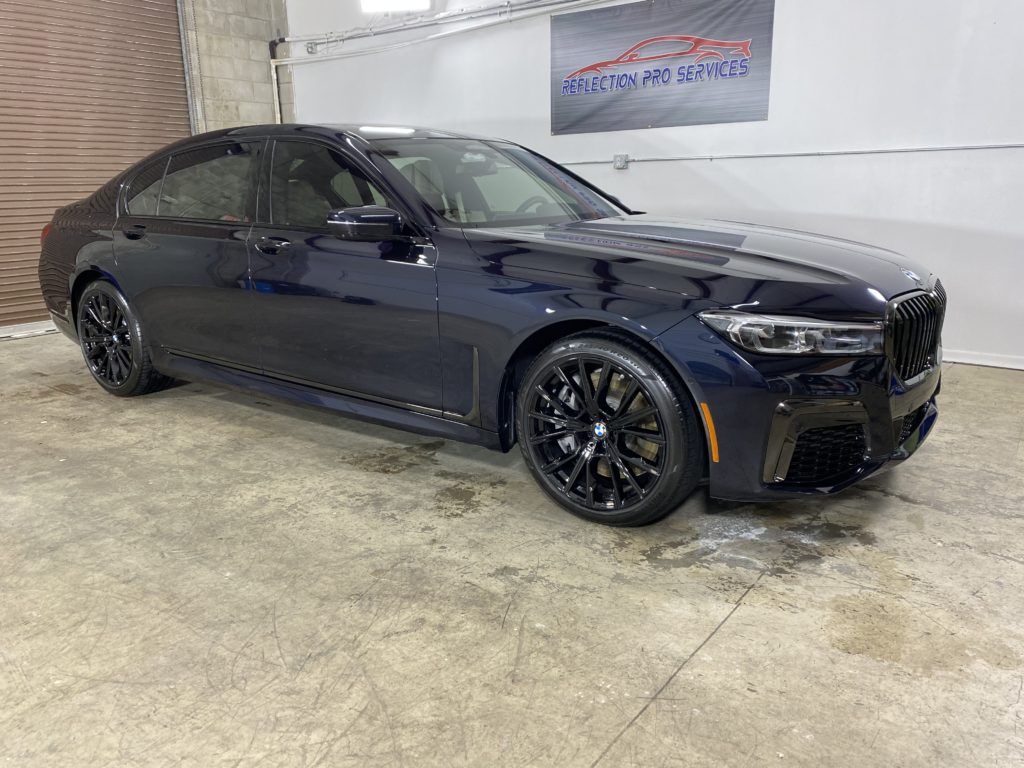 A black bmw 7 series is parked in a garage.