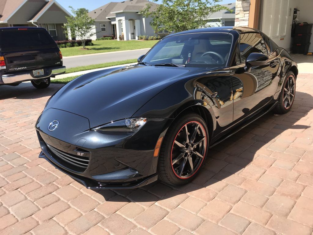A black sports car is parked on a brick driveway.