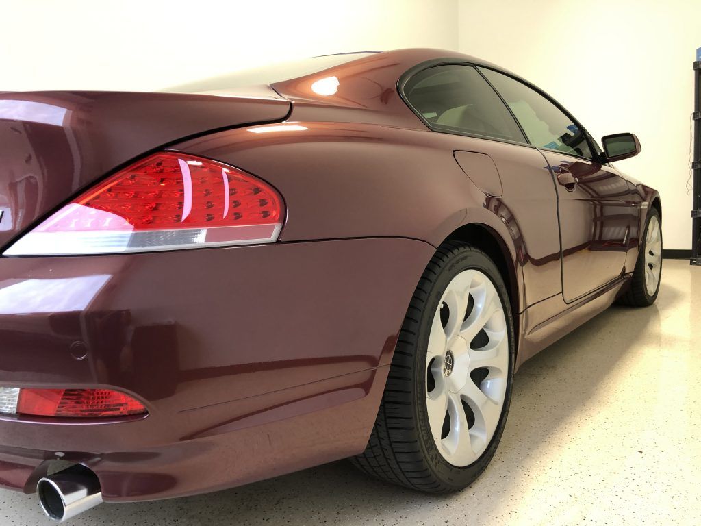 A burgundy bmw is parked in a garage.