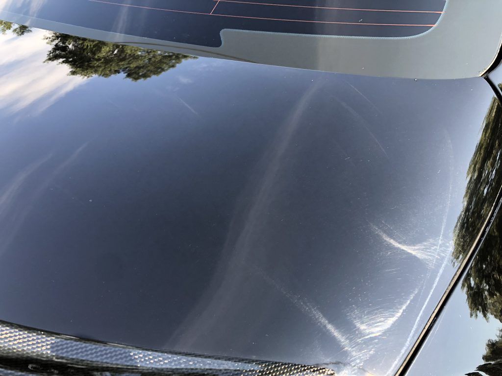 A close up of a car windshield with a reflection of trees in it.