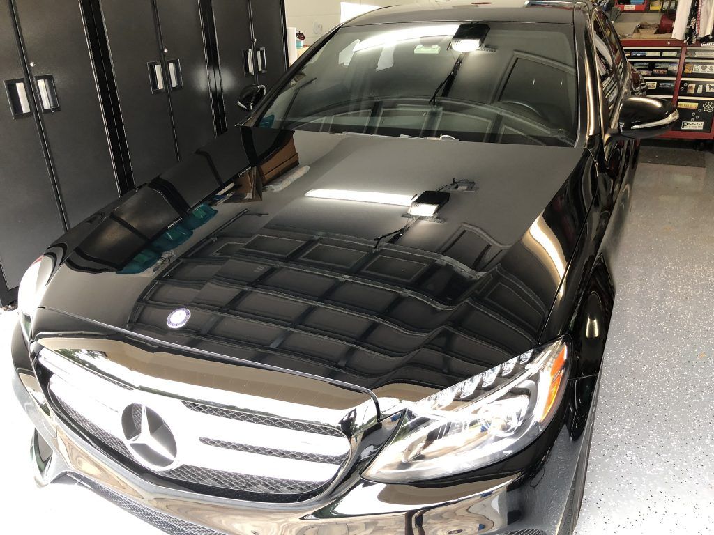 A black mercedes benz is parked in a garage.
