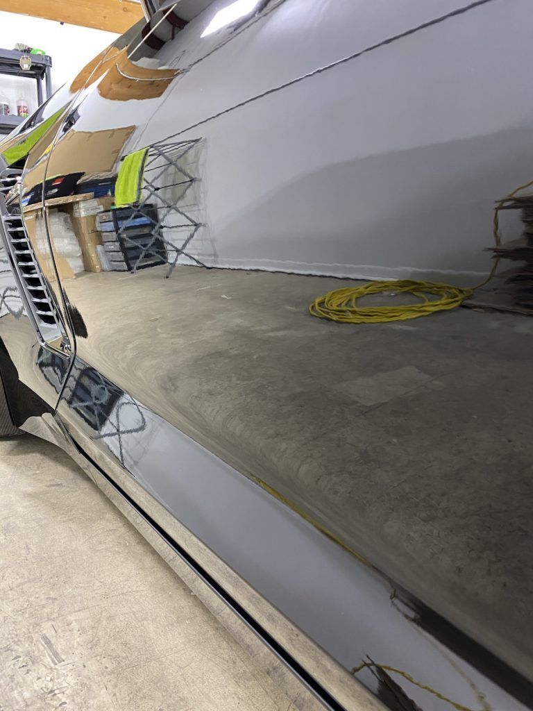 A close up of a car 's side in a garage.