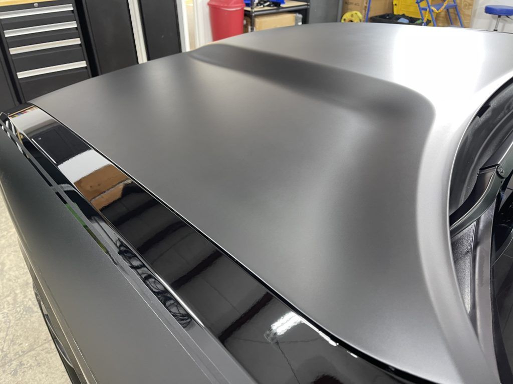 A close up of the hood of a black car in a garage.