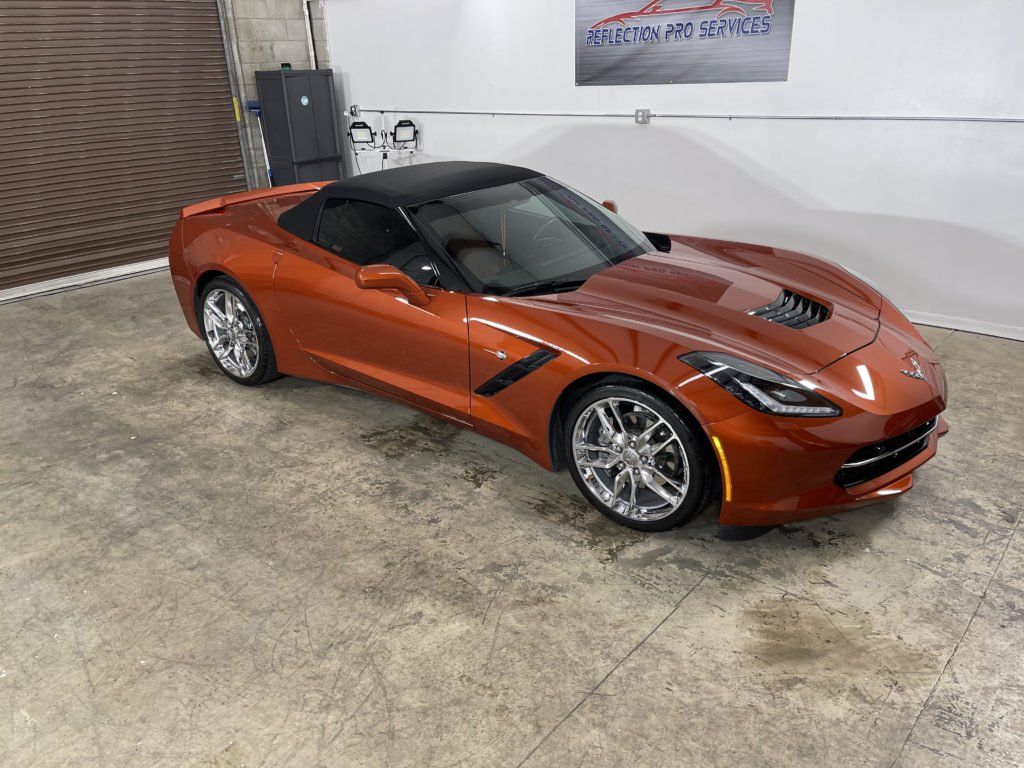 A red corvette convertible is parked in a garage.