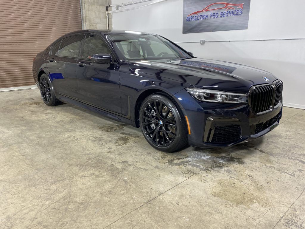 A black bmw 750li is parked in a garage.