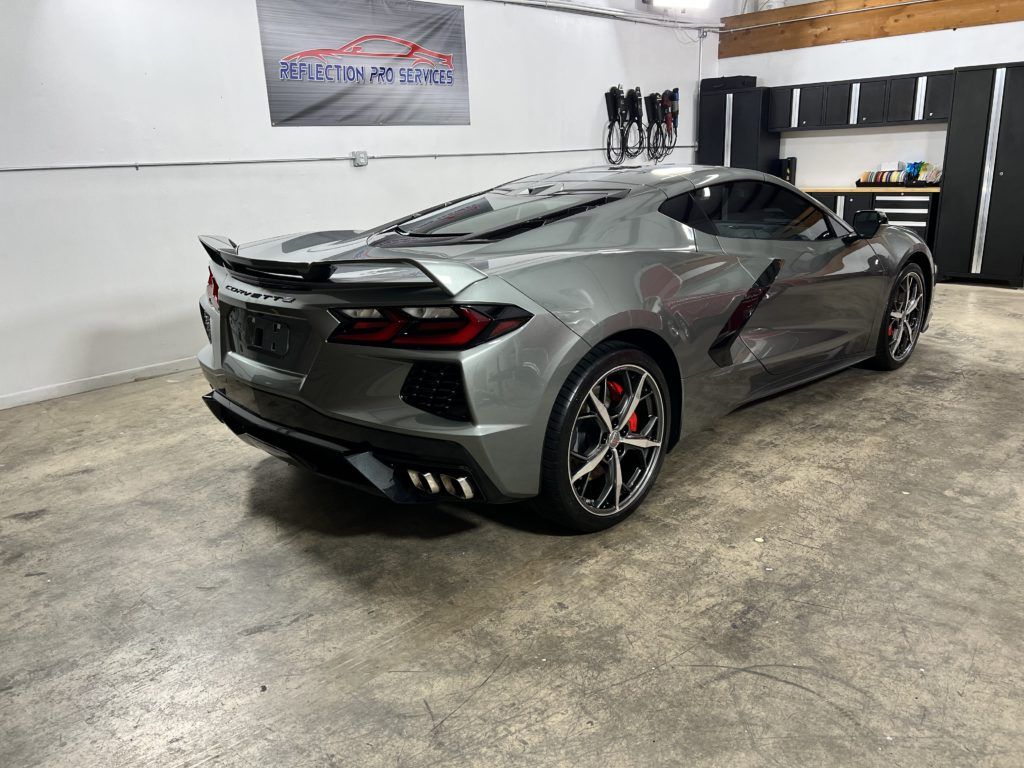 A gray sports car is parked in a garage.