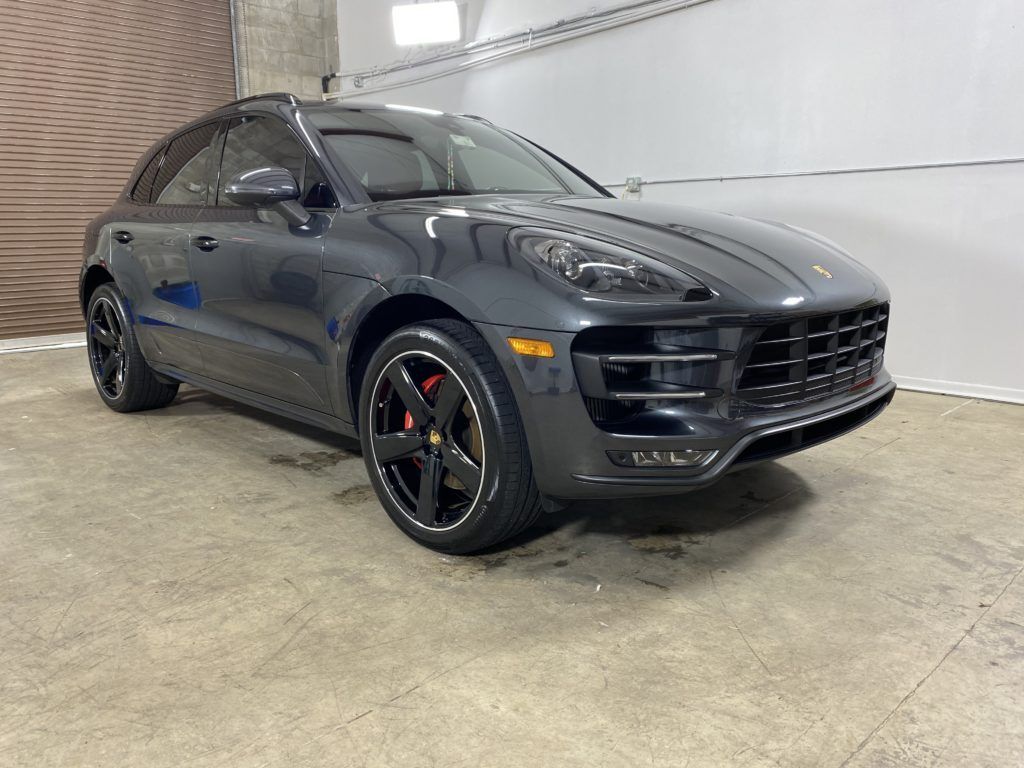 A gray porsche macan turbo is parked in a garage.