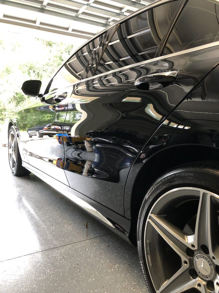 A black mercedes benz is parked in a garage.