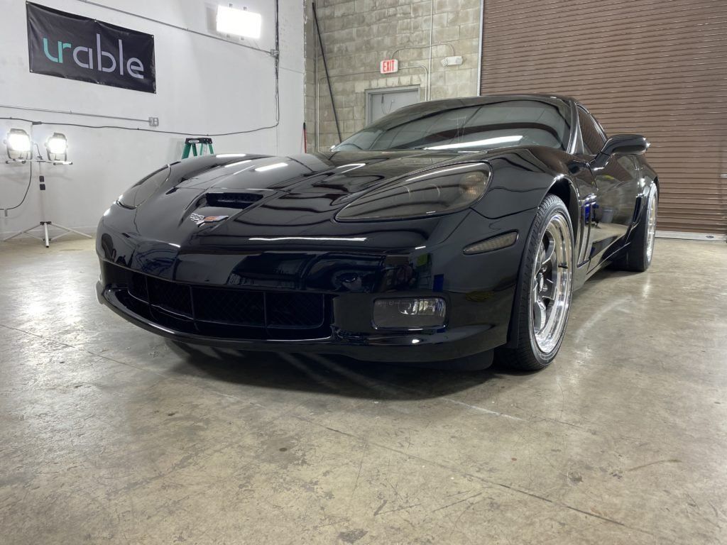 A black sports car is parked in a garage.