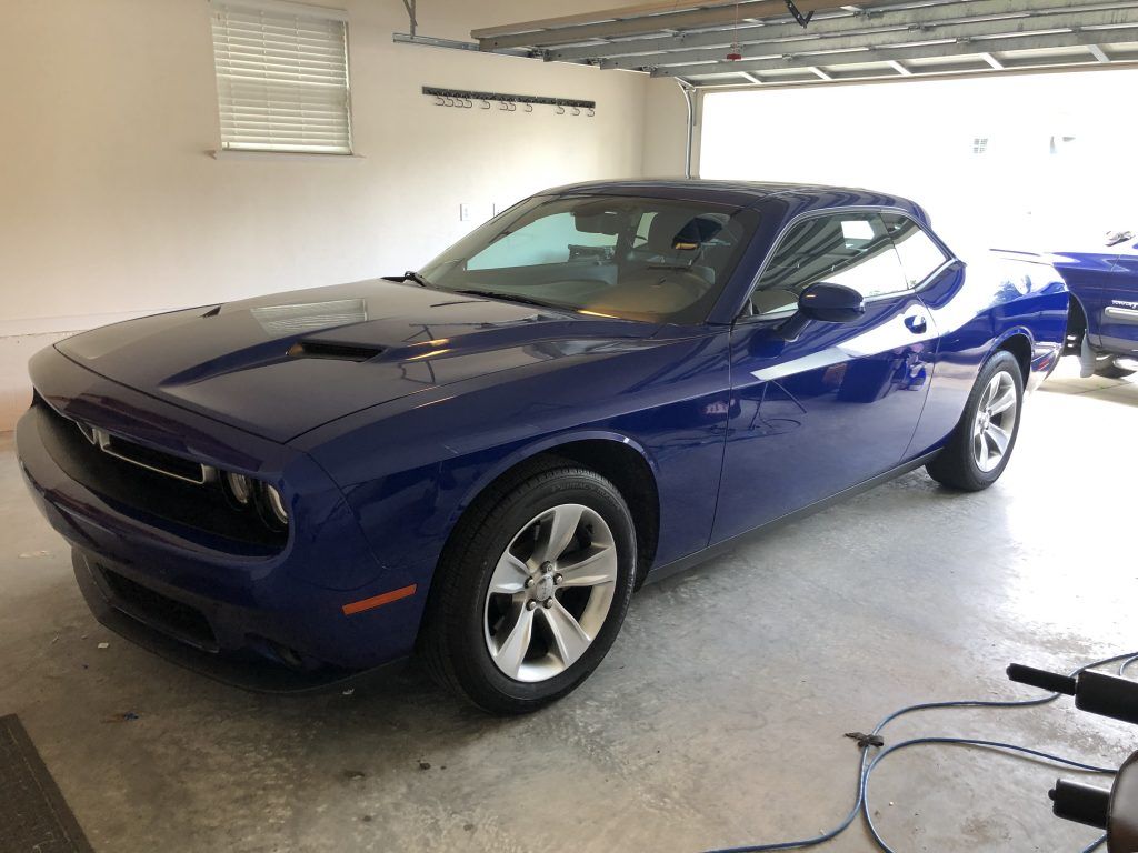 A blue dodge challenger is parked in a garage.