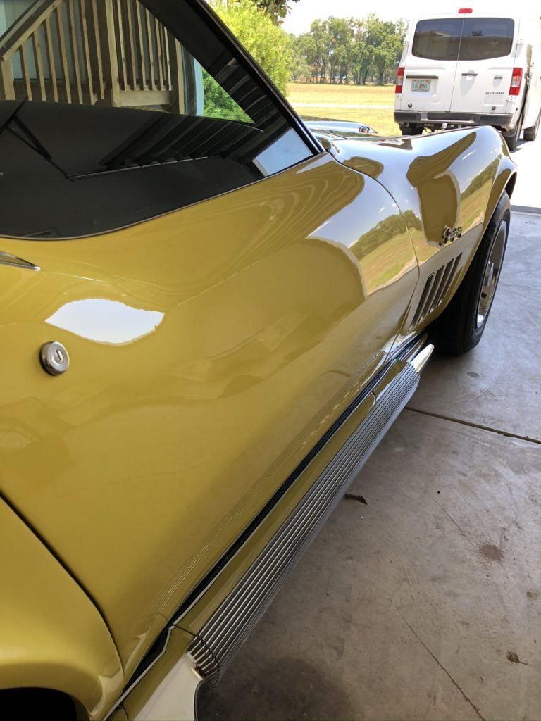 A yellow car is parked in a garage next to a white van.