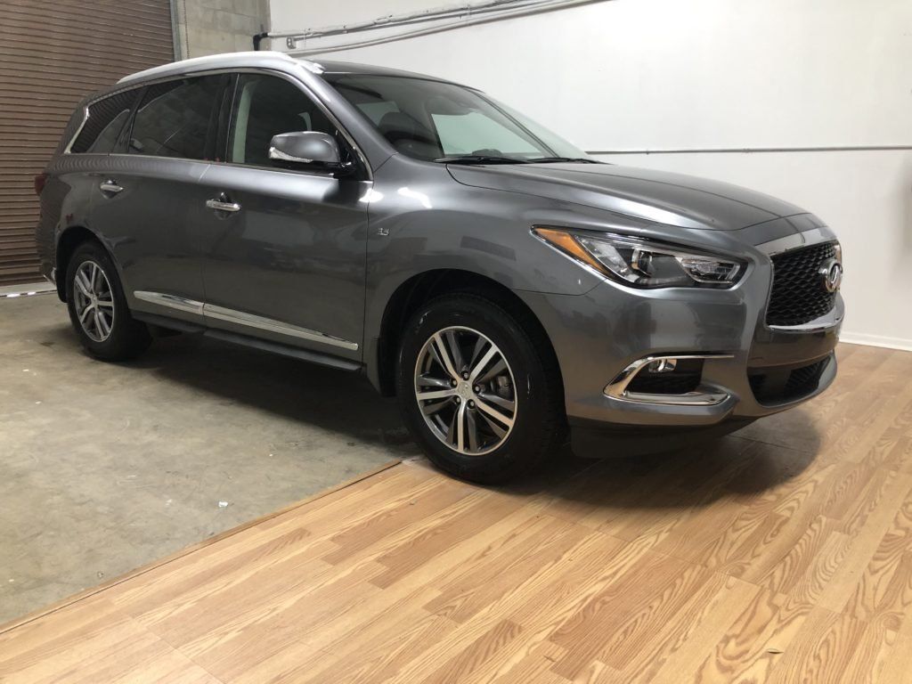 A gray car is parked in a garage next to a wooden floor.