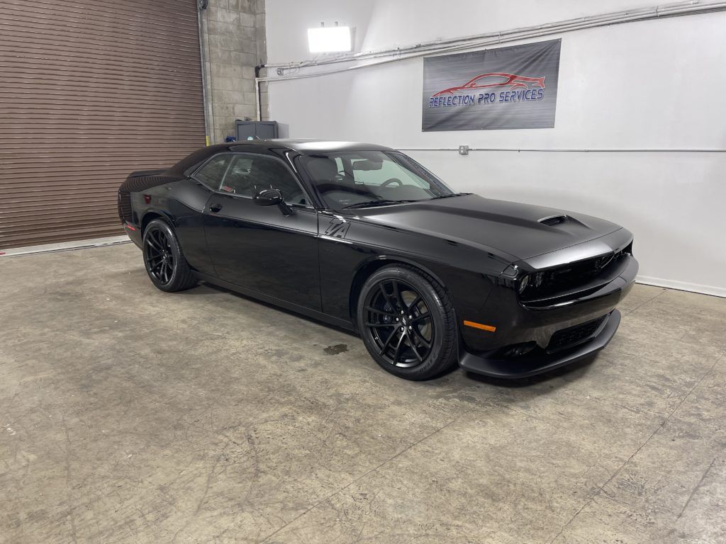 A black dodge challenger is parked in a garage.