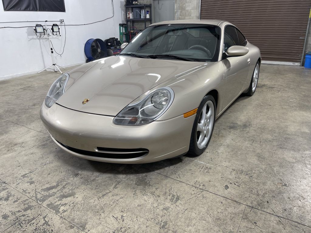 A silver porsche 911 is parked in a garage.