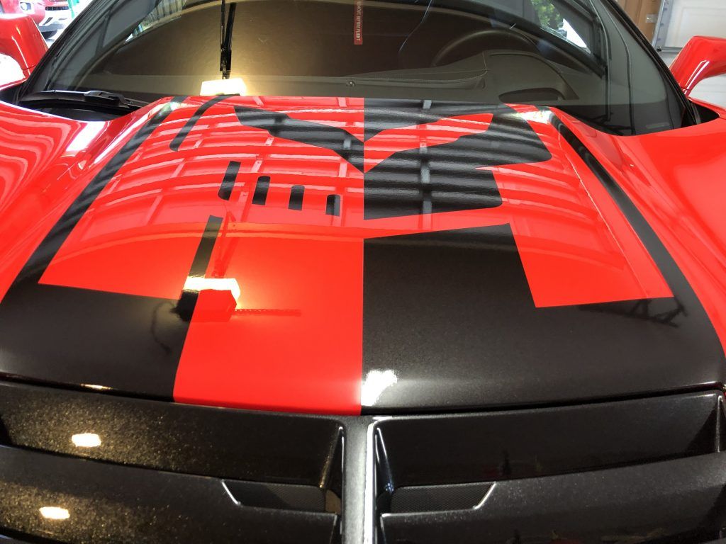 A red car with black stripes on the hood