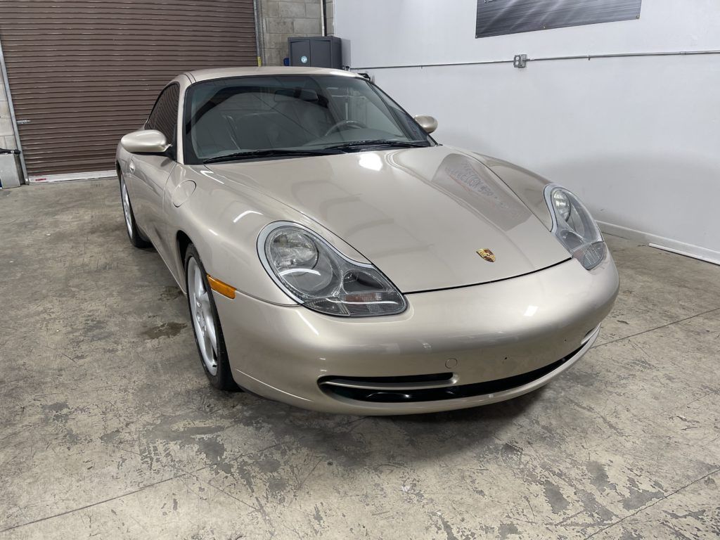 A silver porsche 911 is parked in a garage.