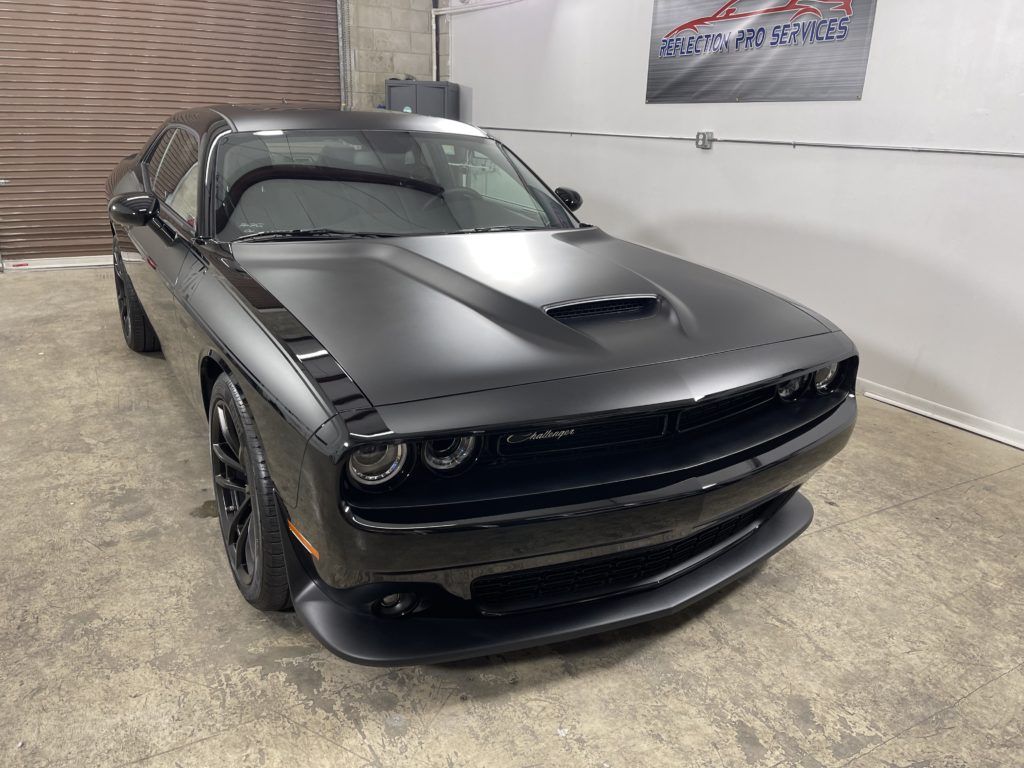 A black dodge challenger is parked in a garage.