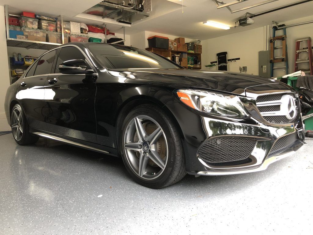 A black mercedes benz c class is parked in a garage.