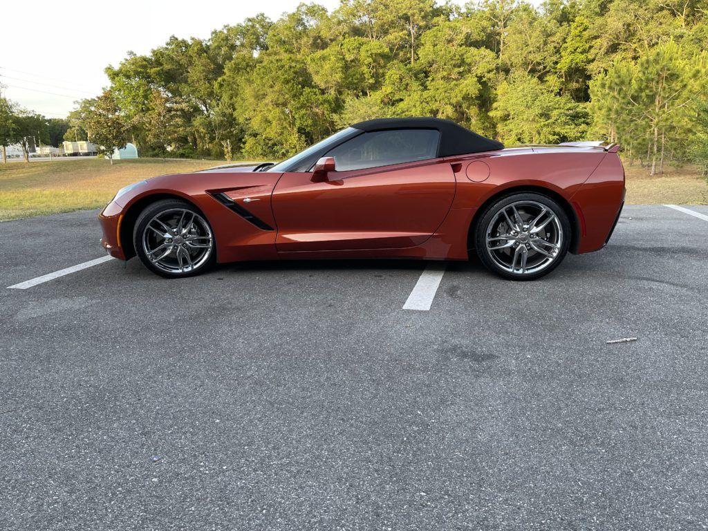 A red corvette convertible is parked in a parking lot.