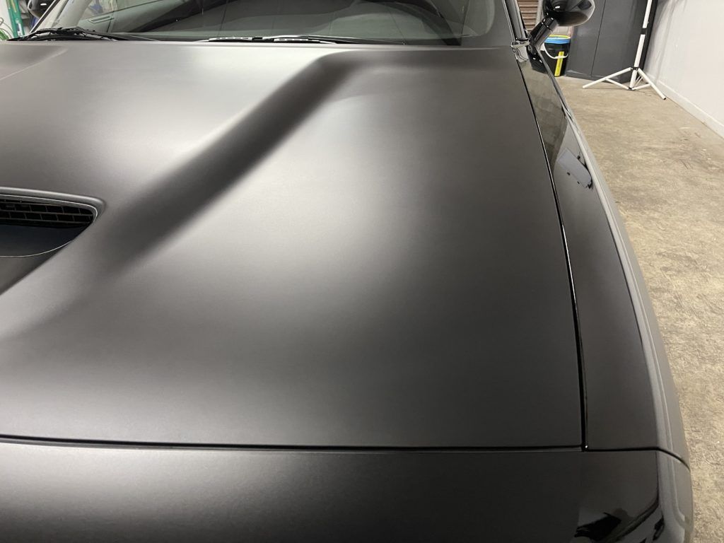 A close up of the hood of a black car in a garage.