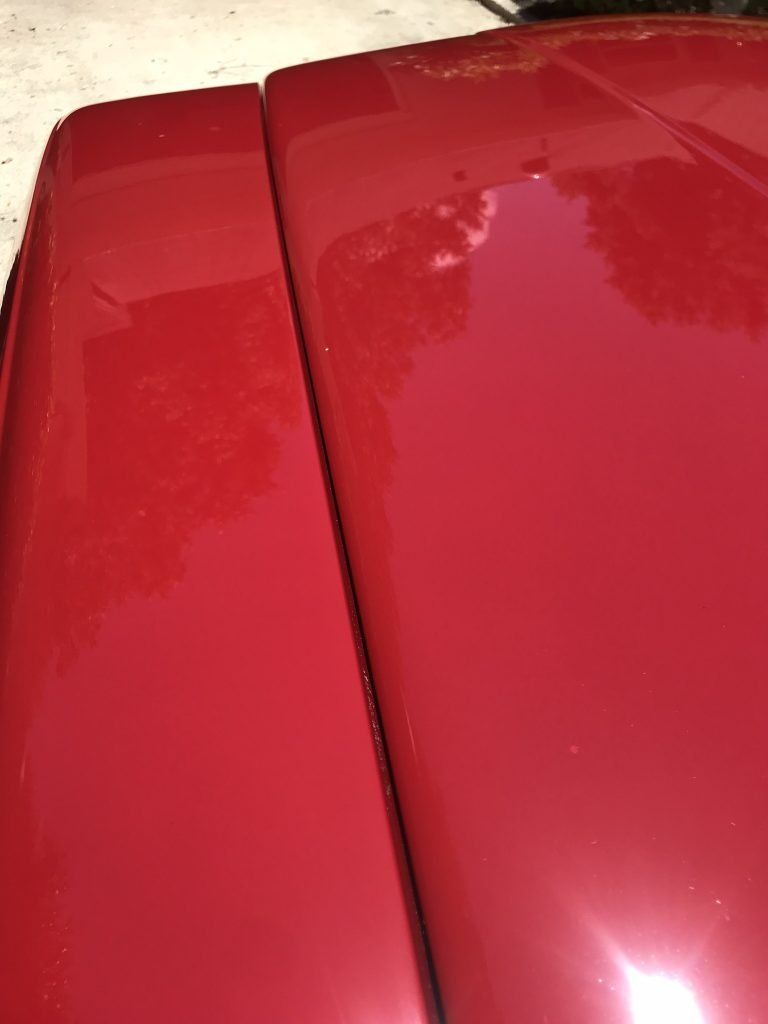 A close up of the hood of a red car.