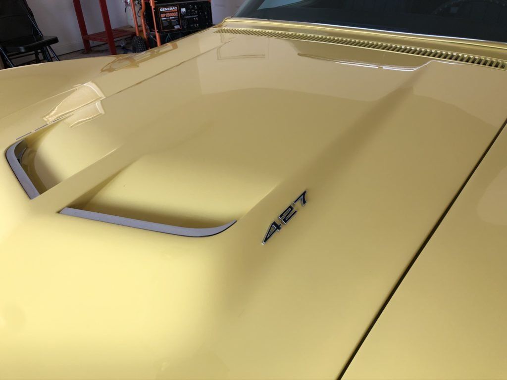 A close up of the hood of a yellow car