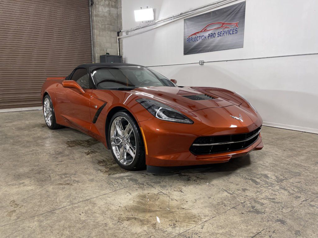 A red corvette convertible is parked in a garage.
