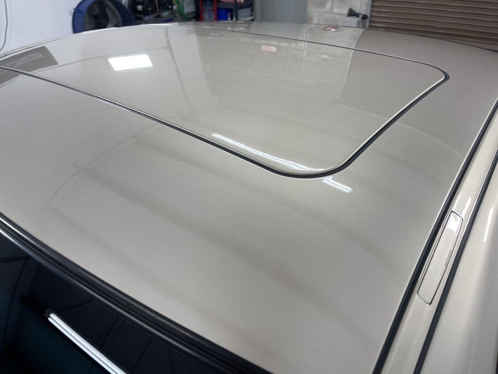 A white car with a sunroof is parked in a garage.