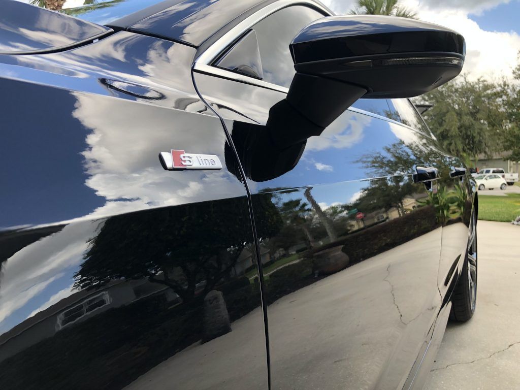 A black car is parked in a driveway in front of a house.