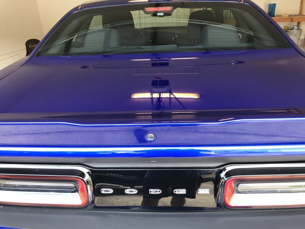 A blue car is parked in a garage with the hood up