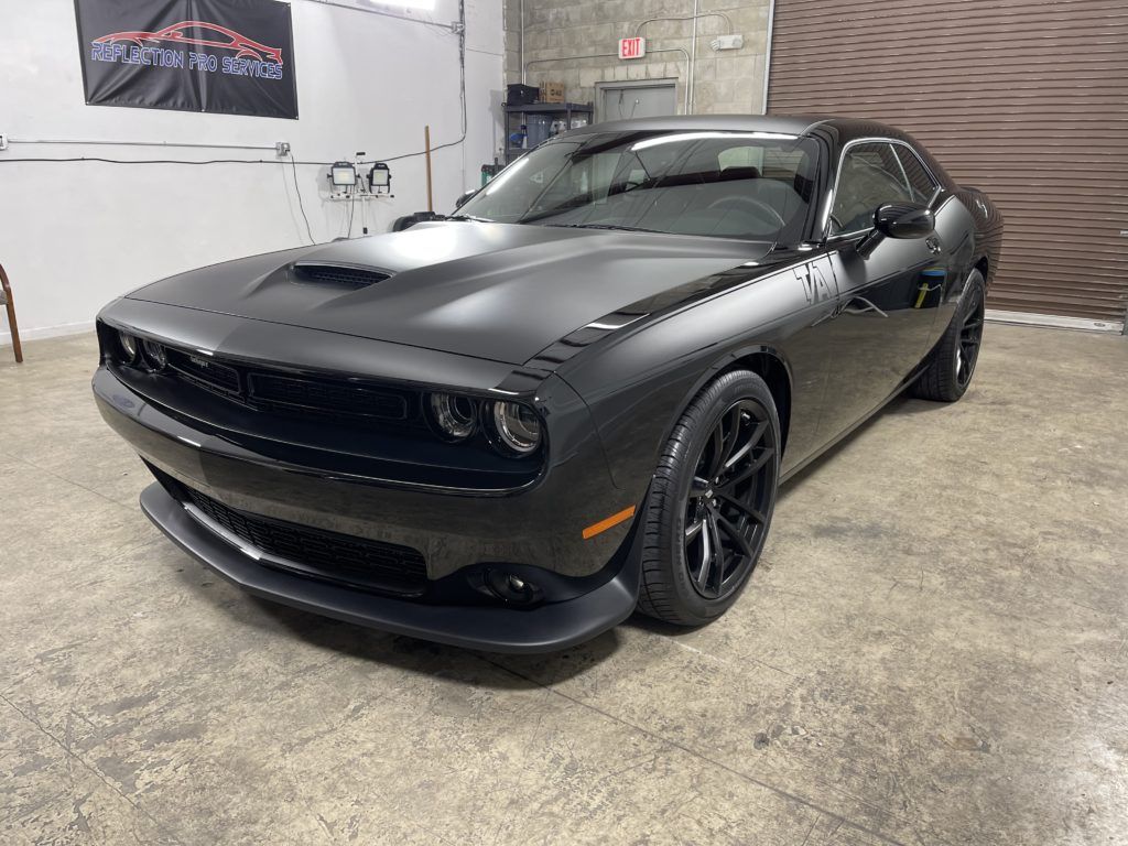 A black dodge challenger is parked in a garage.