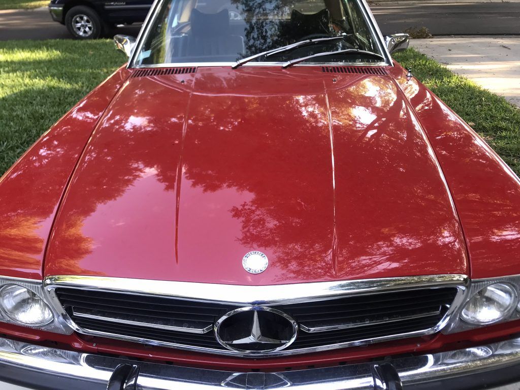A red mercedes benz is parked on the side of the road